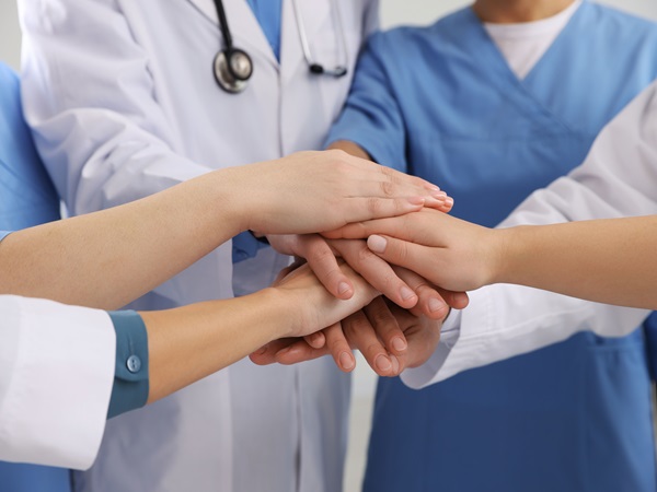 Team of medical doctors putting hands together, closeup